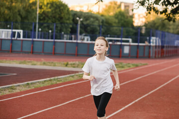 Fototapeta premium Smiling tween girl runner on a racing track. ?hildren healthy active lifestyle and physical education concept.