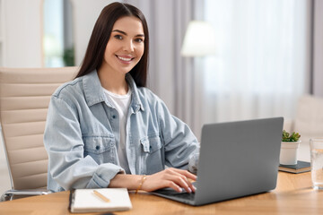 Young woman watching webinar at table in room