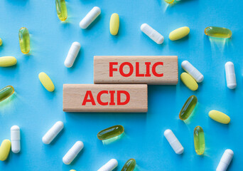 Folic acid symbol. Wooden blocks with words Folic acid. Beautiful blue background with pills. Medicine and Folic acid concept. Copy space.