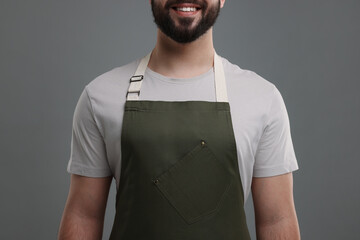 Smiling man in kitchen apron on grey background, closeup. Mockup for design