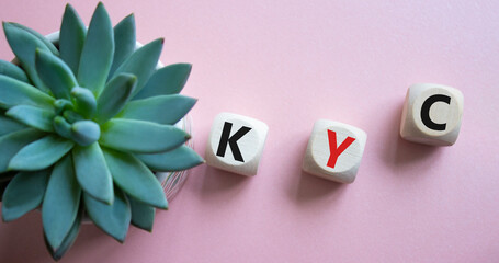 KYC - Know Your Customer. Wooden cubes with word KYC. Beautiful pink background with succulent...