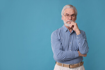 Portrait of stylish grandpa with glasses on light blue background, space for text