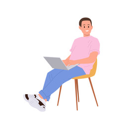 Smiling young man freelancer cartoon character sitting on chair and working online using laptop