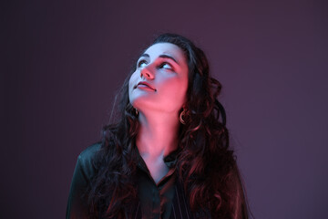 Fototapeta premium Portrait of beautiful young woman on color background with neon lights