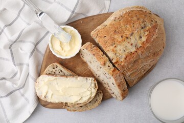 Tasty bread with butter, knife and milk in glass on gray table, flat lay