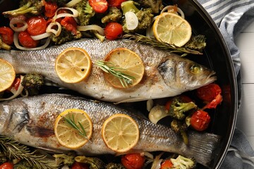 Baked fish with vegetables, rosemary and lemon on white wooden table, top view