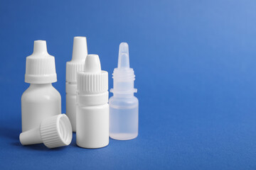 Bottles of medical drops on blue background, space for text