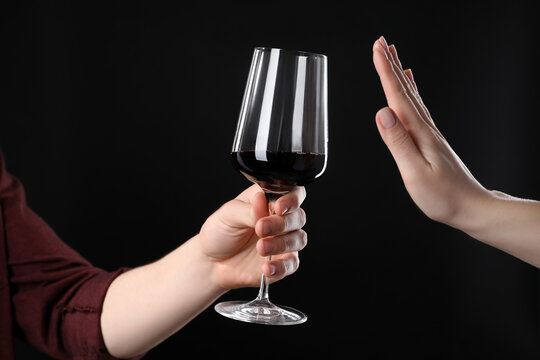 Alcohol addiction. Woman refusing glass of wine on black background, closeup