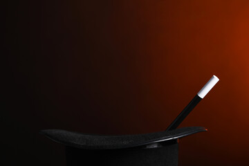 Magician's hat and wand on dark background, closeup. Space for text