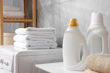 Soft towels, detergents and washing machine indoors, closeup