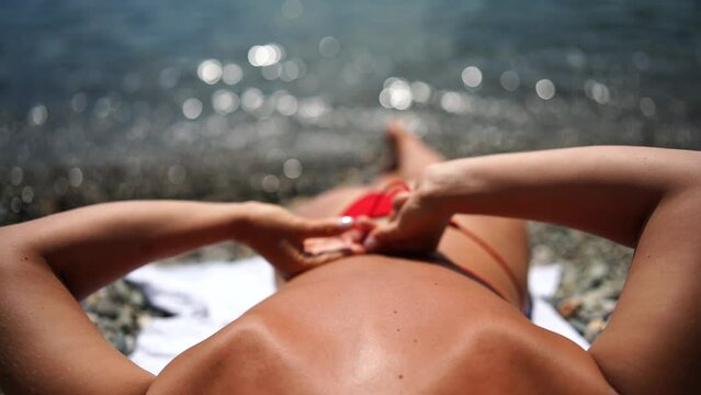 Woman taking red bikini off on beach for tan, lady stripping holiday swimsuit with bow in string. Fun and relax, sexy model untying swimming costume bra, happy woman in swimwear on vacation
