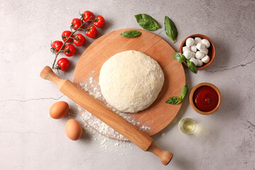 Pizza dough, products and rolling pin on gray textured table, flat lay