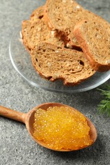 Fresh pike caviar in spoon and bread on grey table