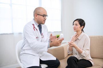 Fototapeta premium Foreign tanned male doctor in white medical clothes discussing woman's illness male doctor opens an iPad, shows treatment and medication information, and provides information of each drug.