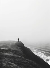 Man standing alone on a cliff overlooking the ocean