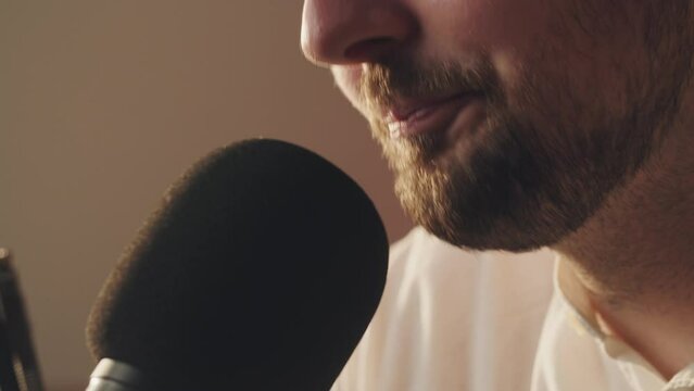Podcast recording. Close up shot bearded guy saying to microphone in his private audio studio. Professional musician records new soundtrack sample. Positive podcaster telling fresh news in live