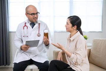 Fototapeta premium Foreign tanned male doctor in white medical clothes discussing woman's illness male doctor opens an iPad, shows treatment and medication information, and provides information of each drug.