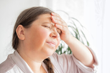 diseased mature woman experiences severe headache, holding head, Hot flashes during menopause,...