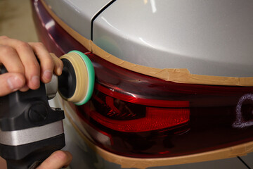Person using a machine to polish automotive lighting on a car headlight