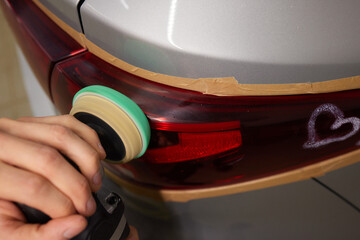 Person using a machine to polish automotive lighting on a car headlight