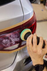 Person using a machine to polish automotive lighting on a car headlight