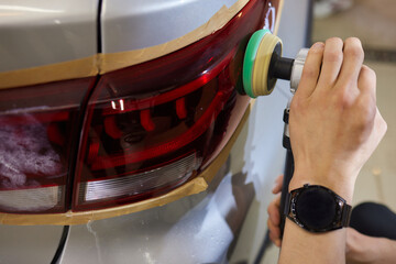 Person using a machine to polish automotive lighting on a car headlight