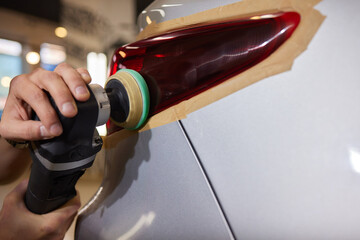 Person using a machine to polish automotive lighting on a car headlight