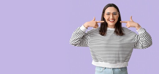 Smiling young woman showing her teeth on lilac background with space for text © Pixel-Shot