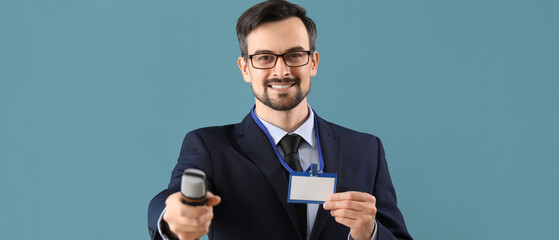 Male journalist with badge and microphone on blue background