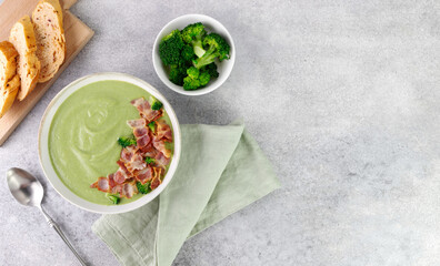 Creamy broccoli soup with bacon and croutons on a gray background. Top view. Copy space.