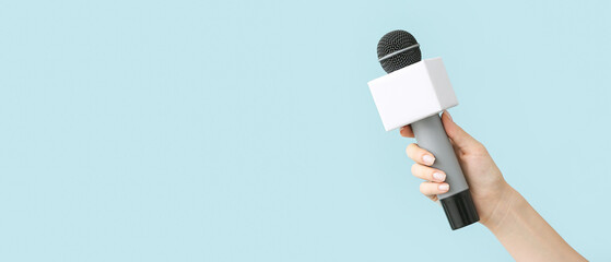 Journalist's hand with microphone on color background