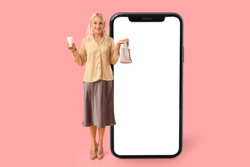 Mature woman with cup of coffee and purse on pink background