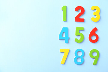 Colorful numbers on light blue background, flat lay. Space for text