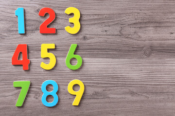 Colorful numbers on wooden school desk, flat lay. Space for text