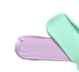 Strokes of pink and purple color correcting concealers on white background, top view