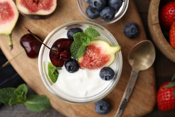 Glass with yogurt, berries and mint on wooden table, flat lay