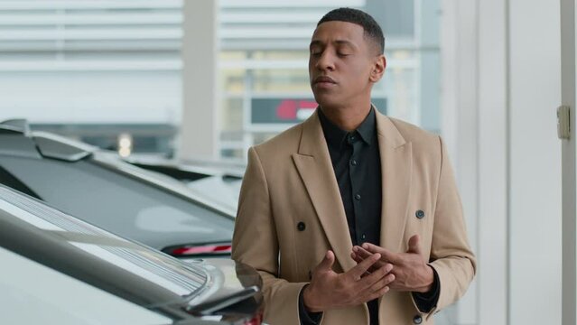 Thoughtful pensive guy male businessman African American man client buyer think choose new automobile in auto salon store thinking puzzled customer think ponder dream buy rent car decision loan credit