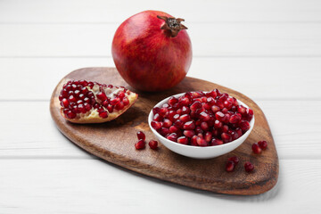Ripe juicy pomegranate with grains on white wooden table