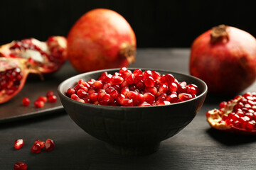 Tasty ripe pomegranates and grains on dark wooden table