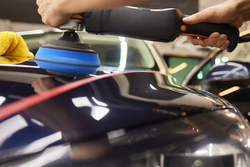 Person using machine to polish black cars automotive exterior