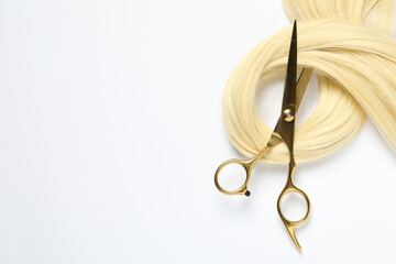 Professional hairdresser scissors with blonde hair strand on white background, top view