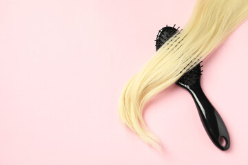 Stylish brush with blonde hair strand on pink background, top view. Space for text