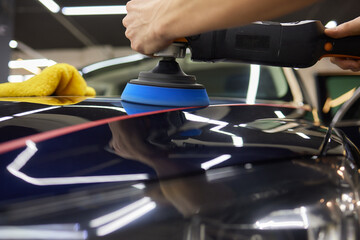 Person using machine to polish black cars automotive exterior