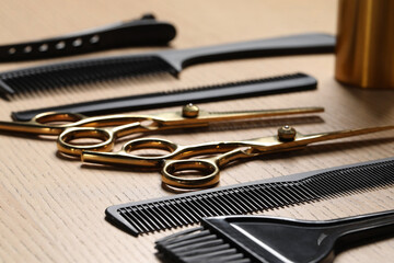 Hairdresser tools. Different scissors and combs on wooden table in salon, closeup