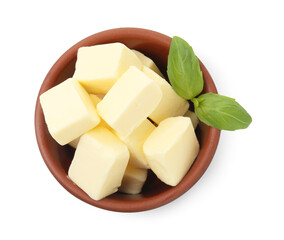 Tasty butter cubes and basil leaves in bowl isolated on white, top view