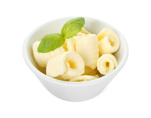 Tasty butter curls and basil leaves in bowl isolated on white