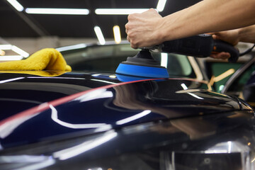Person using machine to polish black cars automotive exterior