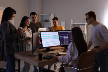 Team of young programmers working at office in evening