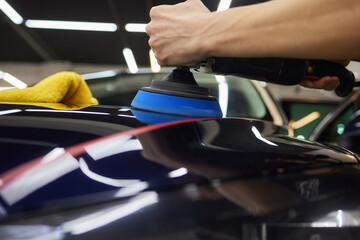 Person using machine to polish black cars automotive exterior