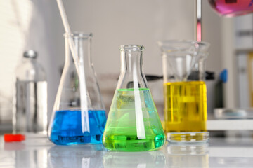Laboratory analysis. Glassware with different liquids on white table indoors, closeup